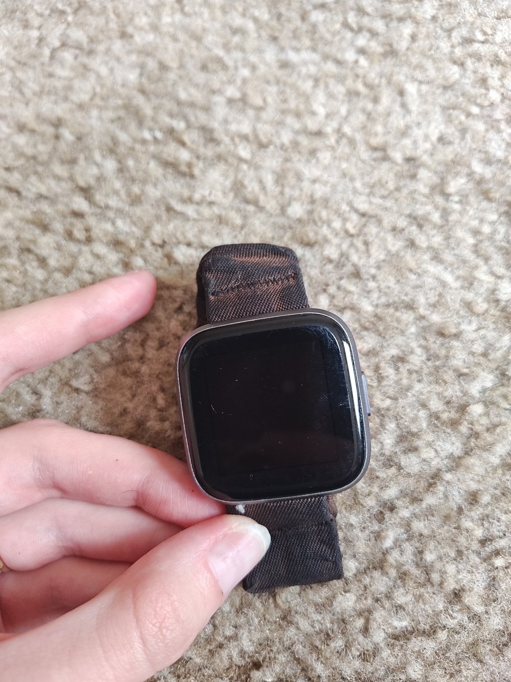 fitbit smartwatch with black screen and brown nylon band